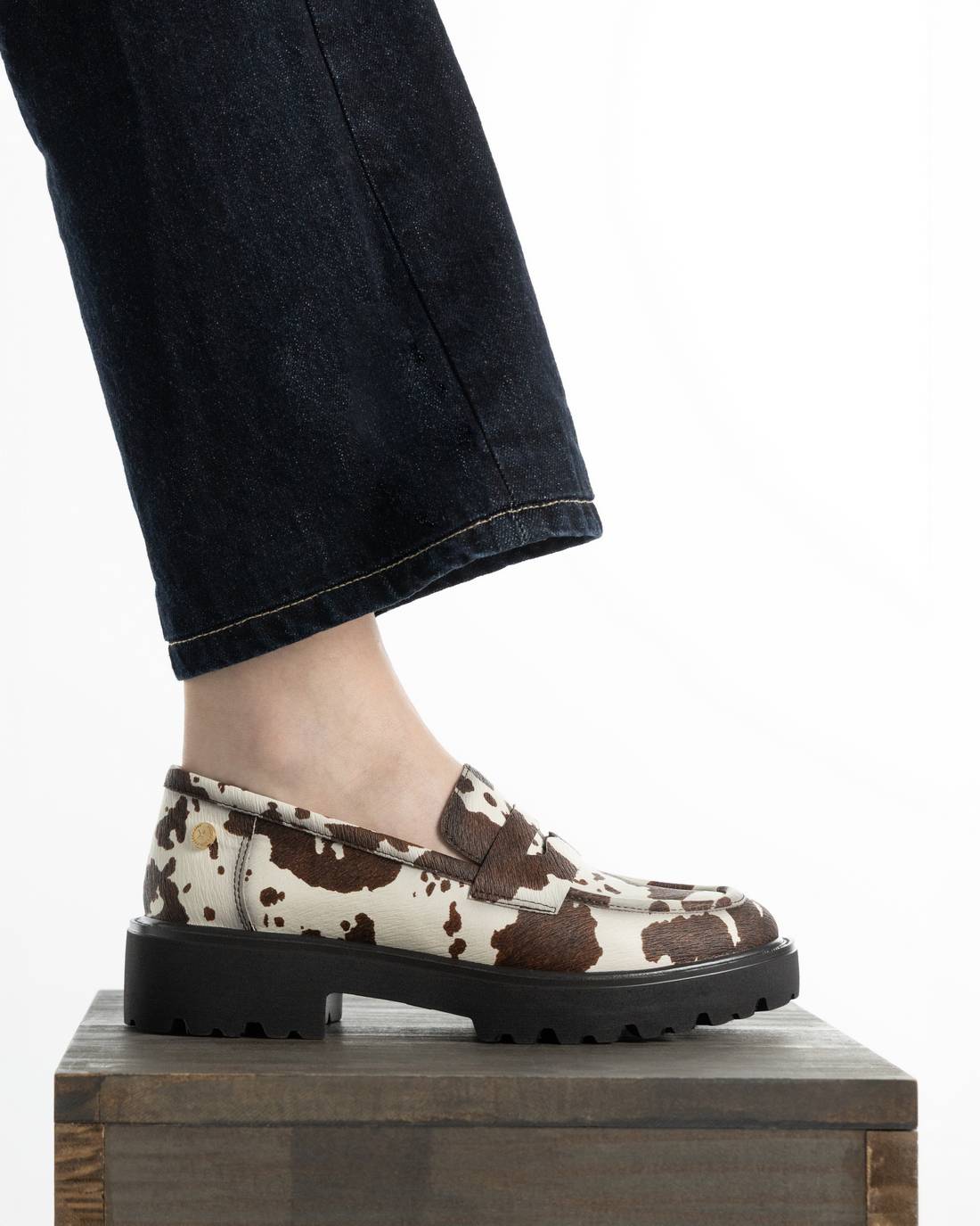 Mocassim XTI de mulher com padrão animal e sola preta, vista lateral no pé