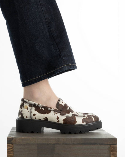 Mocassim XTI de mulher com padrão animal e sola preta, vista lateral no pé